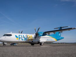 Commercial turboprop aircraft with blue and white livery parked on an airport apron against a clear blue sky