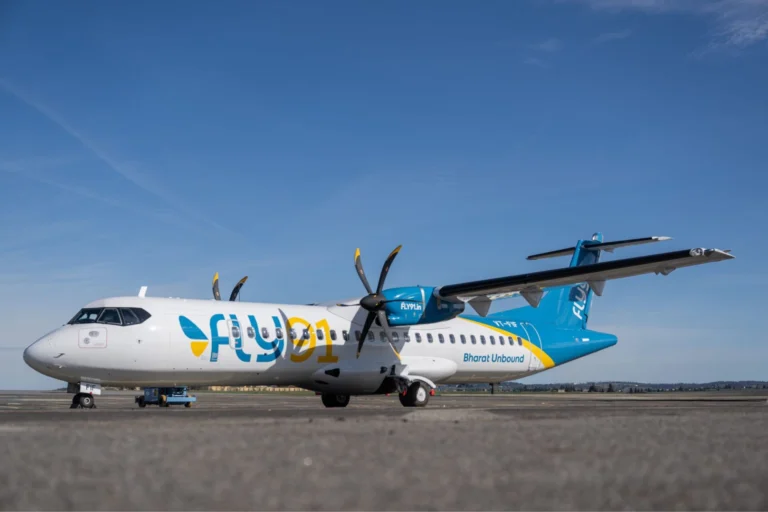 Commercial turboprop aircraft with blue and white livery parked on an airport apron against a clear blue sky
