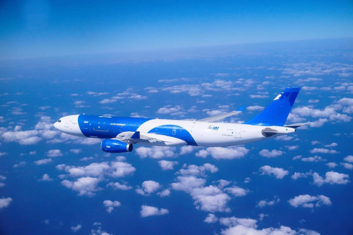 IAIs converted A330 300 freighter completes maiden flight Blue and white commercial airplane cruising above a sea of clouds in a clear blue sky seen from the side of the fuselage and wing