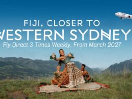 Promotional Fiji banner showing dancers in traditional dress in a field with bold white text FIJI CLOSER TO WESTERN SYDNEY and Fly Direct 3 Times Weekly From March 2027 and a plane in the sky