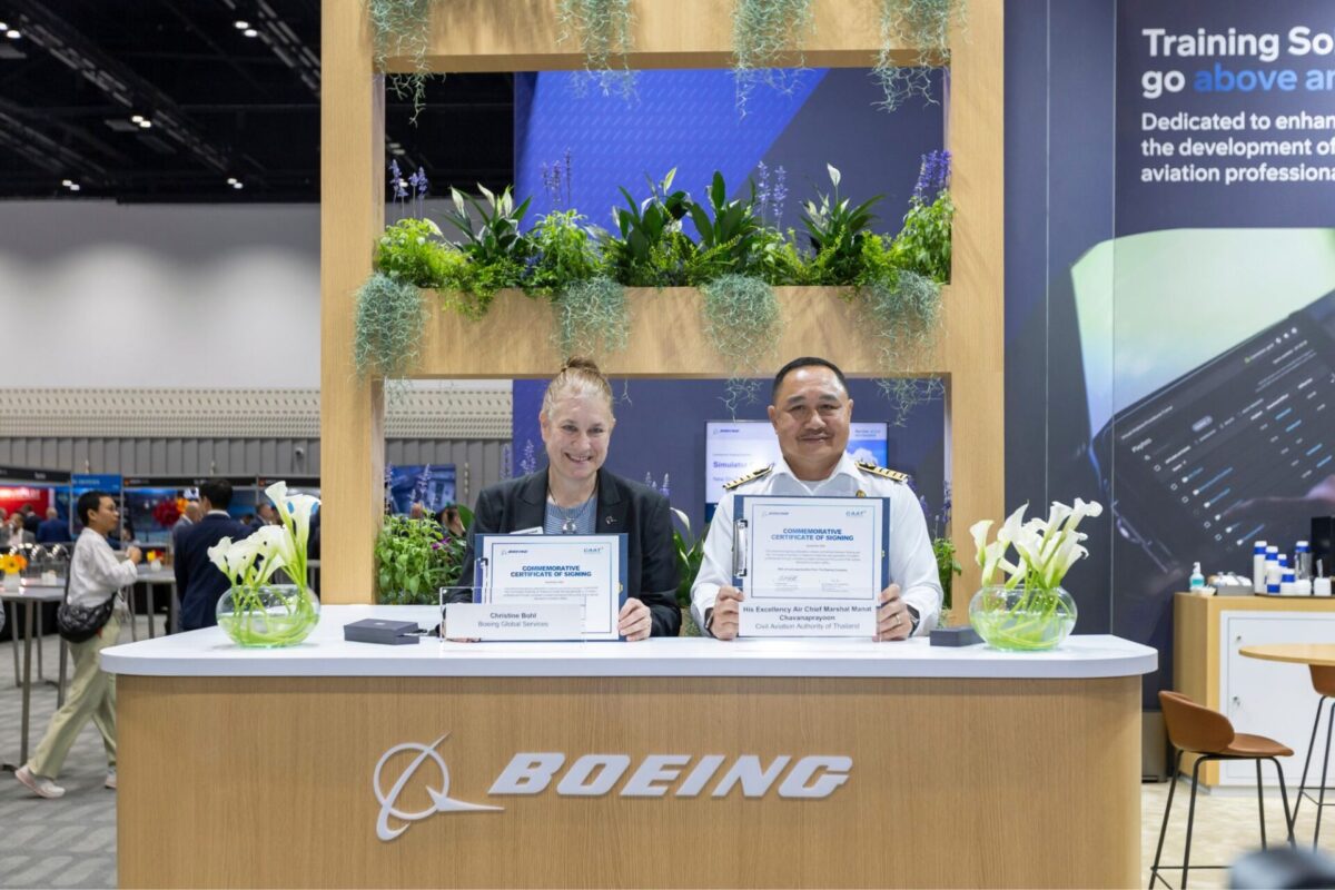 Thailand becomes first to adopt Boeings CBTA pilot training Two professionals at a Boeing exhibition booth display commemorative certificates among greenery