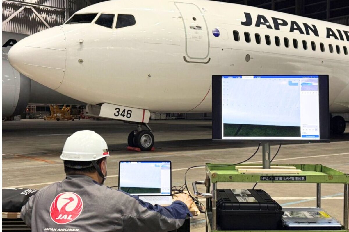 JAL and Donecle launch autonomous drone aircraft inspection Inside a hangar a Japan Airlines jet is parked with technicians at laptops in front of a large monitor displaying system data