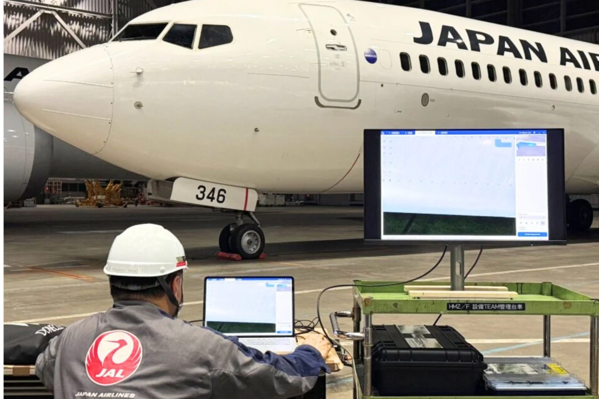 JAL and Donecle launch autonomous drone aircraft inspection Inside a hangar a Japan Airlines jet is parked with technicians at laptops in front of a large monitor displaying system data