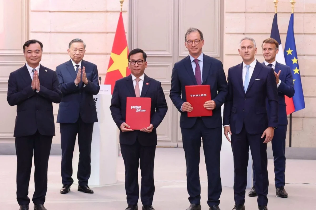 Vietjet and Thales sign major MRO and AI deals in Paris Six men in suits stand on a stage with flags in the background two hold red folders labeled vietjetaircom and THALES