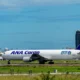 Airliner with ANA Cargo livery on the taxiway at a sunny airport with blue sky and control tower in the background