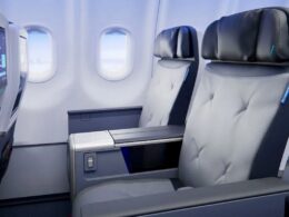 Premium airplane cabin with two gray cushioned seats and a shared center console between them