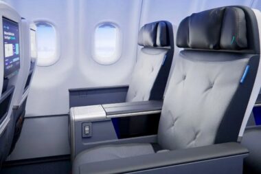 Premium airplane cabin with two gray cushioned seats and a shared center console between them