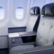 Premium airplane cabin with two gray cushioned seats and a shared center console between them
