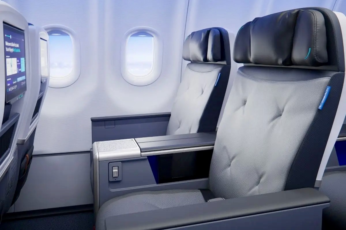 Wide Recliner 01 V03 Resized Premium airplane cabin with two gray cushioned seats and a shared center console between them