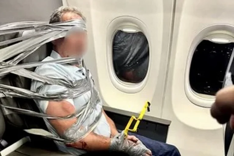 Person bound to an airplane seat with duct tape holding a yellow safety tool near the armrest beside a window