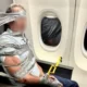 Person bound to an airplane seat with duct tape holding a yellow safety tool near the armrest beside a window