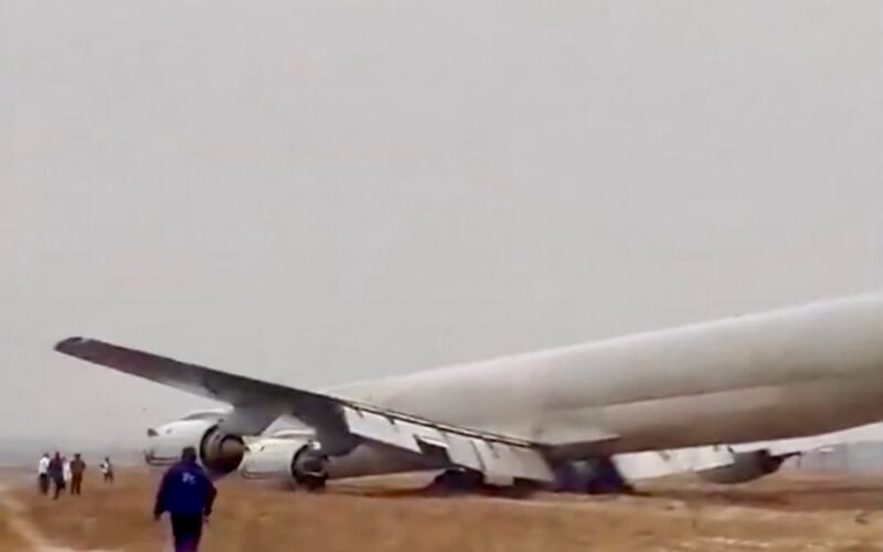dc8congo A large passenger jet lies wrecked on a dirt airfield wings damaged and fuselage crumpled while several people stand nearby observing