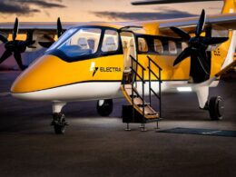 Yellow and white Electra passenger aircraft parked on the tarmac with boarding stairs deployed and open door at dusk twilight