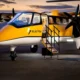 Yellow and white Electra passenger aircraft parked on the tarmac with boarding stairs deployed and open door at dusk twilight