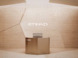 Bronze reception desk against a light tan wall with the Etihad logo and the word London nearby