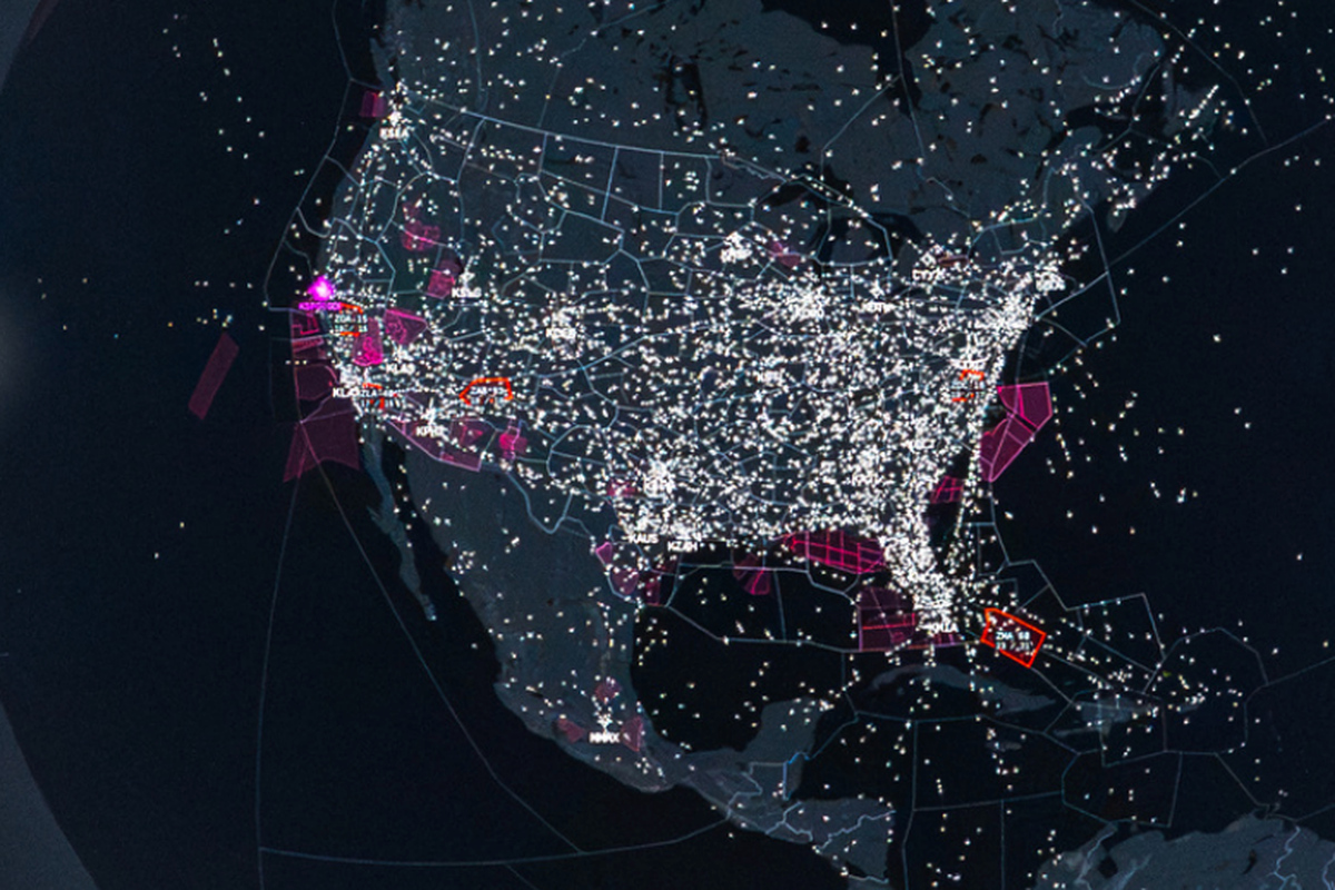 Nighttime map visualization showing dense air traffic with white dots and flight paths across a region magenta hubs and red outlined areas highlight key airports or zones