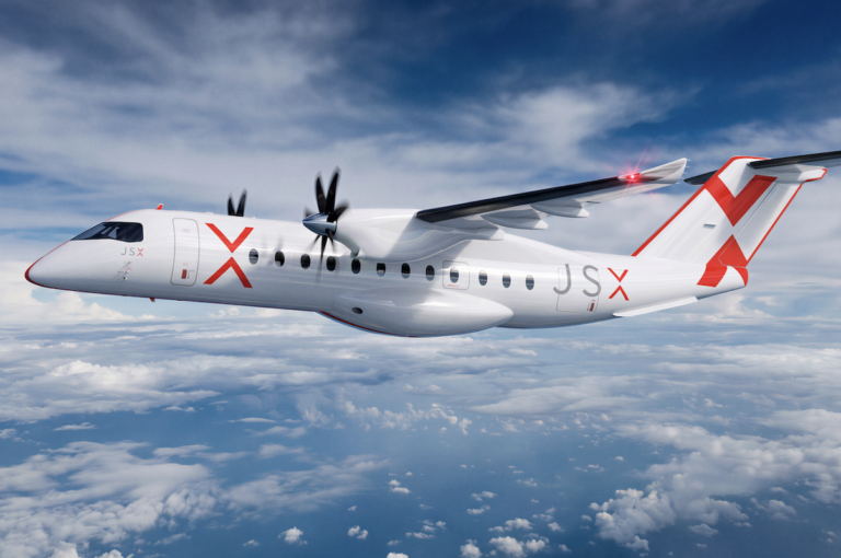 White twin turboprop regional jet in flight over a cloudy blue sky with red JSX branding on fuselage and tail