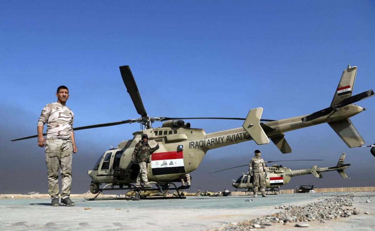 iraq bell407m Iraqi Army helicopter on a desert airstrip with soldiers standing nearby under a blue sky