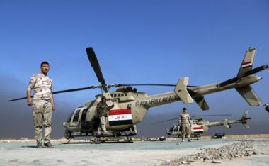 iraq bell407m Iraqi Army helicopter on a desert airstrip with soldiers standing nearby under a blue sky