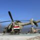 Iraqi Army helicopter on a desert airstrip with soldiers standing nearby under a blue sky