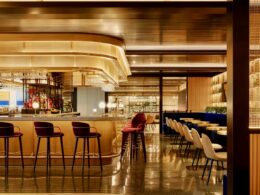 Sleek hotel bar with a curved amber counter red bar stools and warm ambient lighting