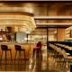 Sleek hotel bar with a curved amber counter red bar stools and warm ambient lighting