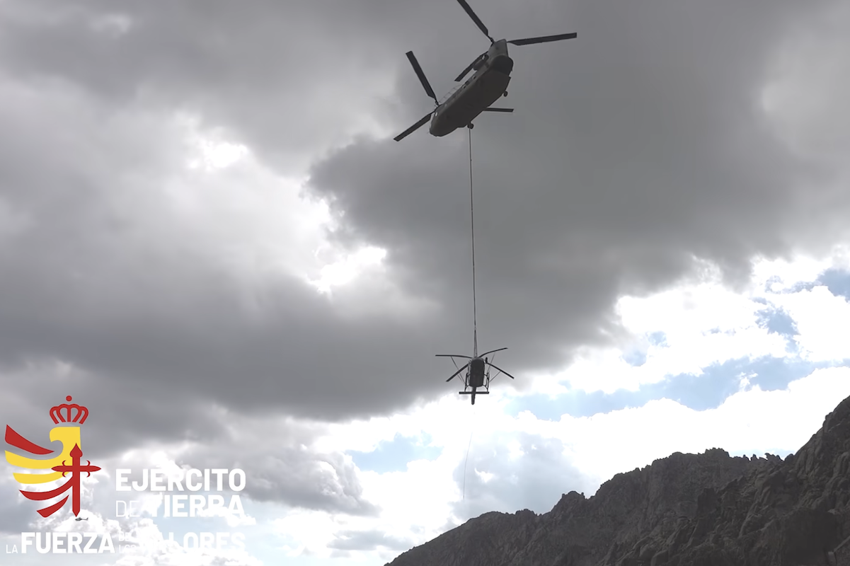spain chinook Military helicopter with long line lowering a suspended load over a rocky mountain landscape logo reading Ejército de Tierra in the corner