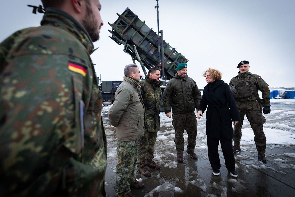 A Patriot air defense system protecting NATOs logistics hub in Poland Group of soldiers in camouflage and a woman in a black coat stand outdoors in snow near a large rocket launcherた