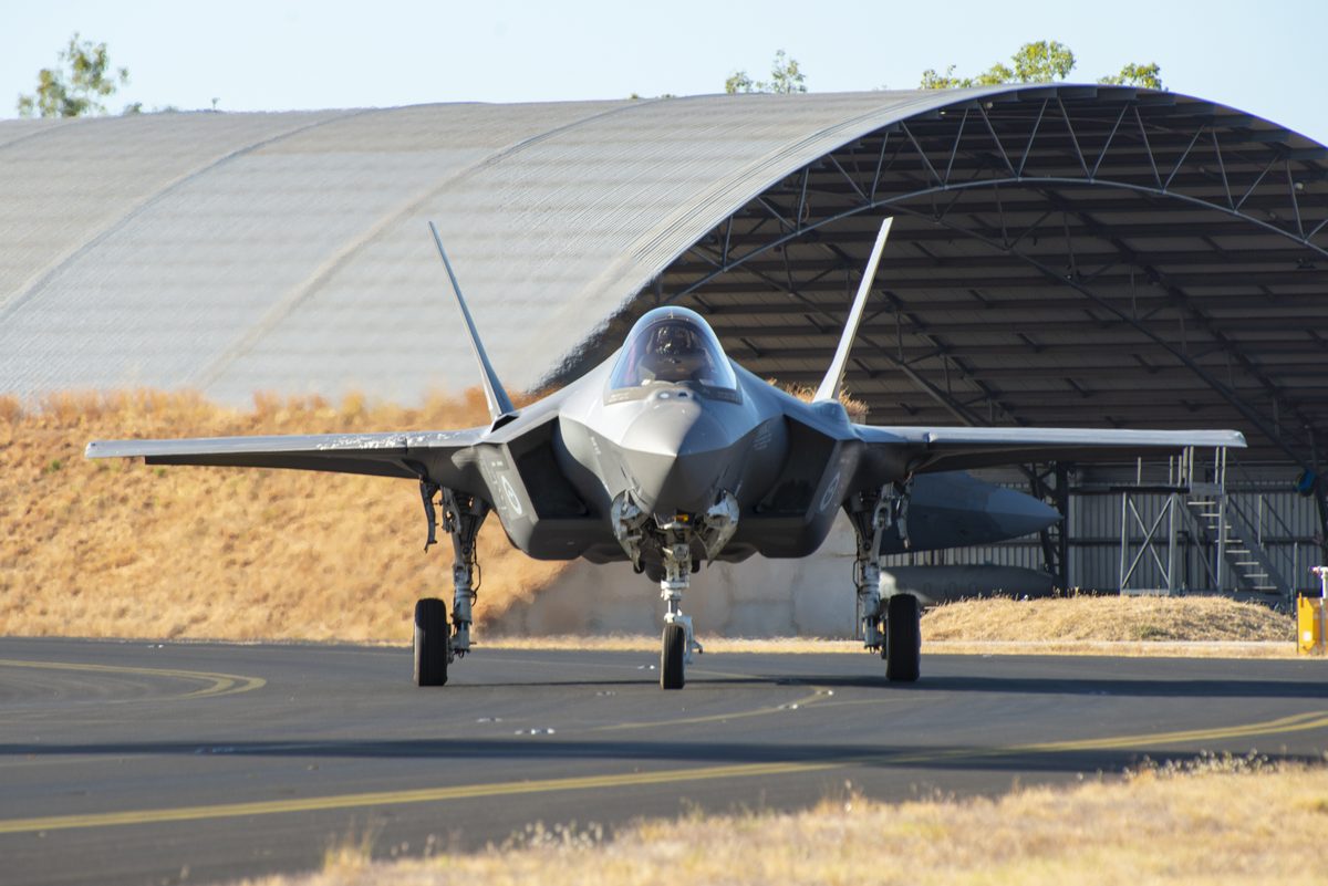 A Royal Australian Air Force F 35A Lightning II from No 75 Squadron taxis at RAAF Base Tindal F 35 fighter jet facing the camera on a runway with a large curved hangar in the background