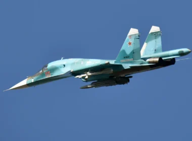 Russian fighter jet in teal livery with red star insignia and the number 15 flying against a clear blue sky
