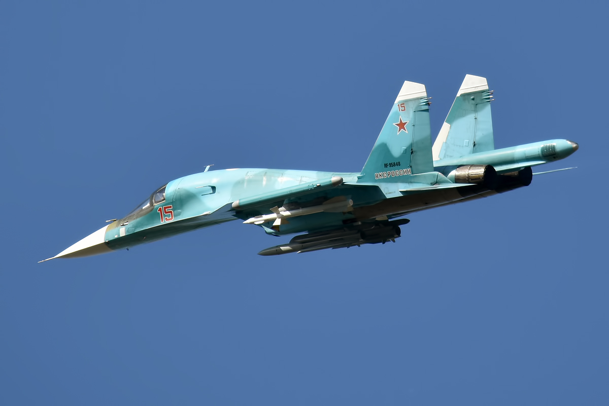 A Russian Air Force Sukhoi Su 34 fighter bomber in flight Russian fighter jet in teal livery with red star insignia and the number 15 flying against a clear blue sky