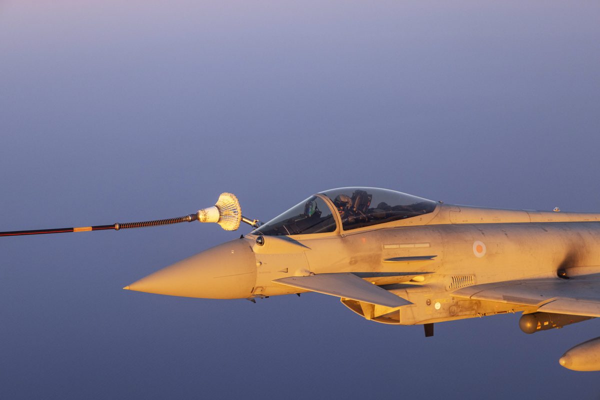 UK Carrier Strike Group on Operation Highmast Military fighter jet connects to a drogue for midair refueling against a blue sky at sunset
