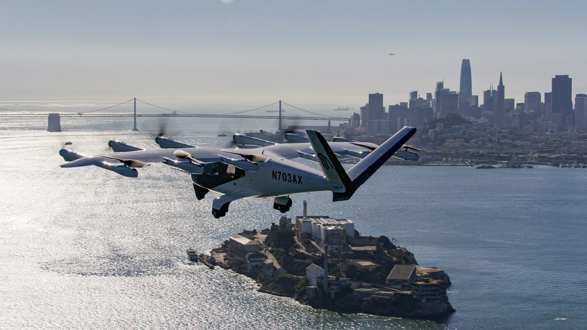 Archer Bay Area No Roads Tour Still 04 Six white seaplanes flying in formation over the bay with San Franciscos skyline and a suspension bridge in the distance