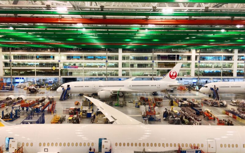 Boeing South Carolina assembly line 26135377557 Inside a spacious aircraft maintenance hangar with a Japan Airlines plane and green and red overhead beams above the tarmac area