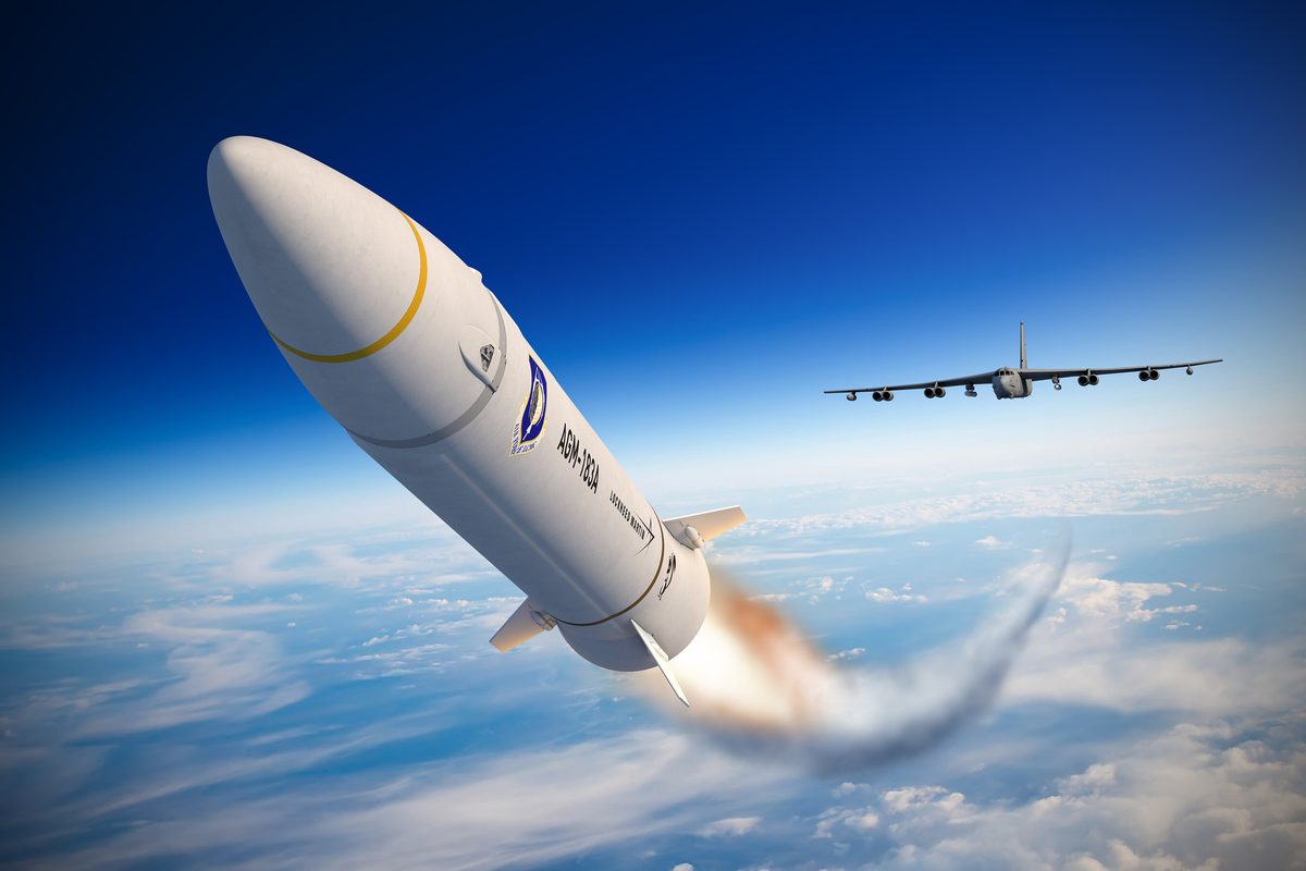 Lockheed Martin AGM 183A Air Launched Rapid Response Weapon ARRW launched from a US Air Force B 52H Stratofortress Close up of a white missile with a yellow ring and emblem flying above clouds with a distant aircraft in view