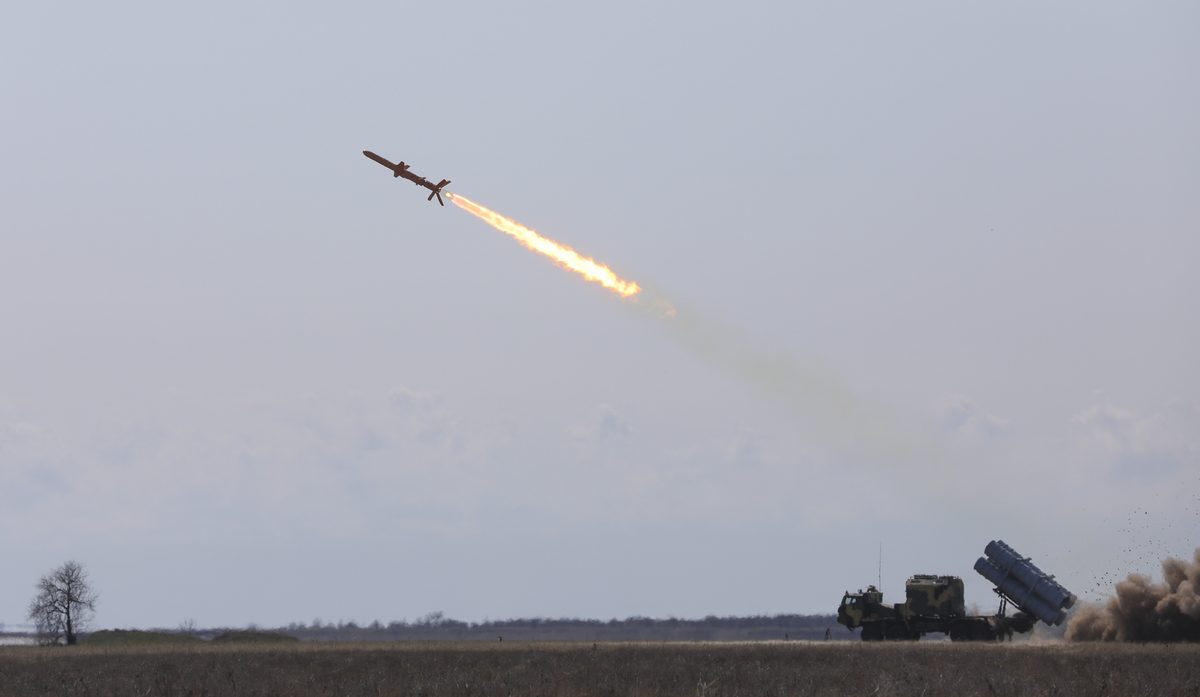 Neptune missile launch Missile launching from a ground site leaving a bright flame trail across the daytime sky with military equipment visible on the right