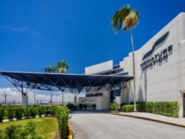 Signature Aviation building with a large blue canopy over the entrance and palm trees under a sunny blue sky