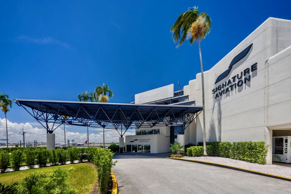 Recently Saved 1 of 1 13 Signature Aviation building with a large blue canopy over the entrance and palm trees under a sunny blue sky