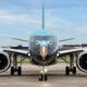 Front view of a blue airplane on the tarmac with an eagle face design on the nose and cockpit windows above
