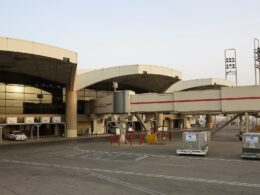 Airport terminal with curved jet bridges and glass facade ground equipment and vehicles on the tarmac