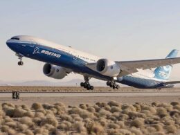 Boeing passenger jet lifting off from a desert runway with shrubs in the foreground