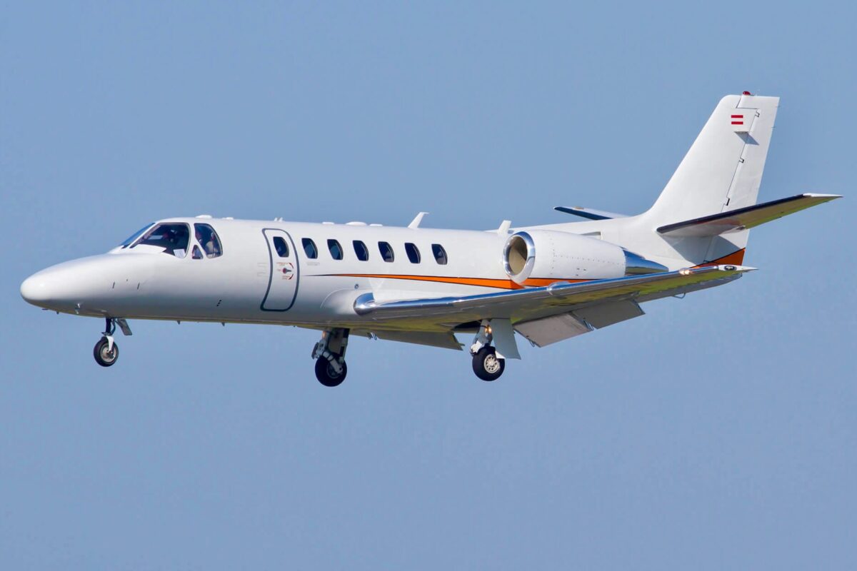 Recently Saved 1 of 1 32 White business jet in flight against a clear blue sky with an orange stripe along the fuselage and gear extended for landingapproach tailswept