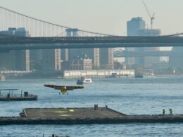 Seaplane taking off from a river with city bridges and skyscrapers in the background