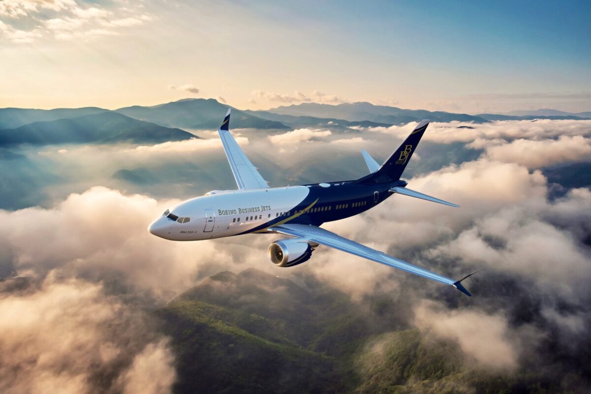 Recently Saved 1 of 1 Boeing Business Jets airplane flying above clouds over mountain range at sunrise