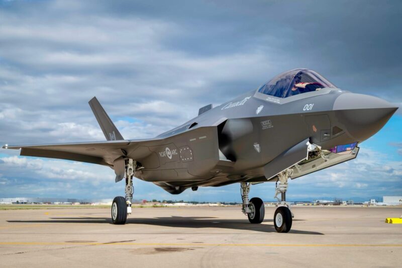 Recently Saved 1 of 1 8 Side view of a gray stealth fighter jet on a tarmac cockpit canopy closed landing gear down in bright daylight under a cloudy sky