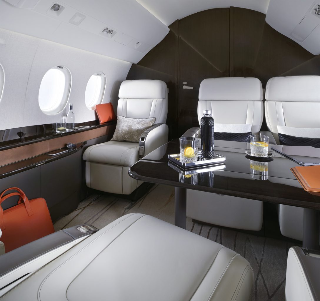 The passenger cabin of a Dassault Falcon 2000LXS business jet Luxurious private jet cabin with white leather seats a glossy dark table and drinks on display