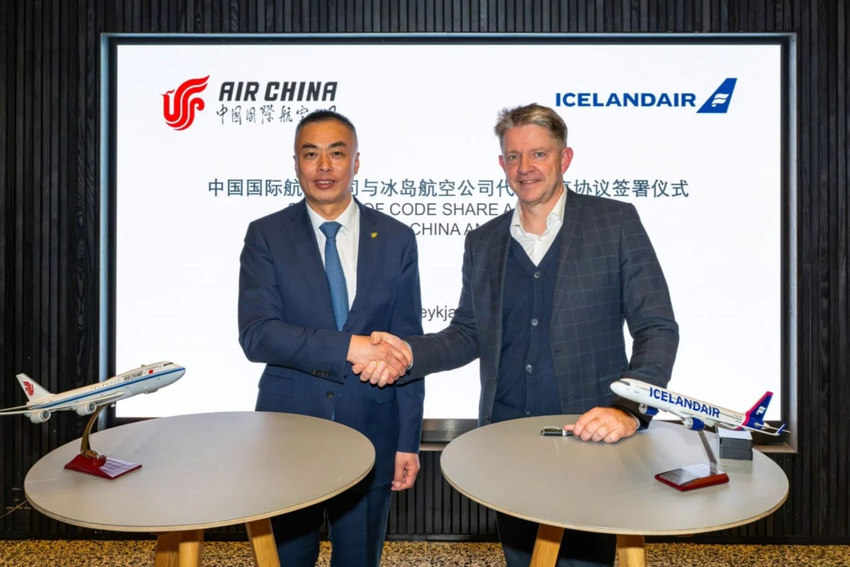 Icelandair and Air China partner to link Iceland and China Two men in suits shake hands in front of a signage with Air China and Icelandair logos model airplanes on round tables nearby