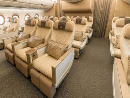 Premium airplane cabin with beige quilted seats plush headrests and patterned cushions arranged in rows beside windows