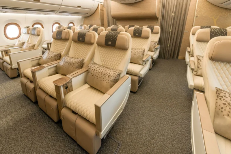 Premium airplane cabin with beige quilted seats plush headrests and patterned cushions arranged in rows beside windows
