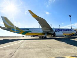Cebu Pacific jet on the tarmac with a colorful yellow and blue tail under a bright sunny sky